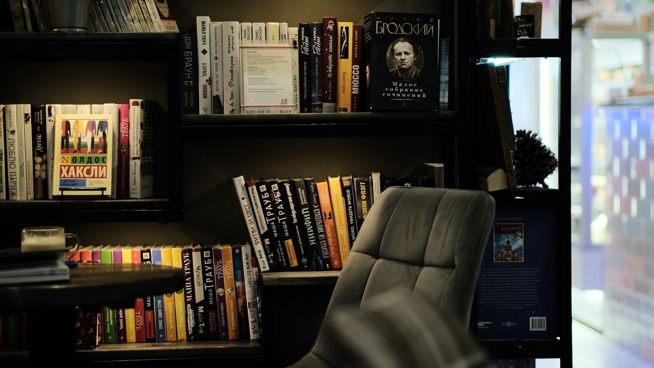 Modern office spot with bookshelf featuring a variety of books and stylish armchair.