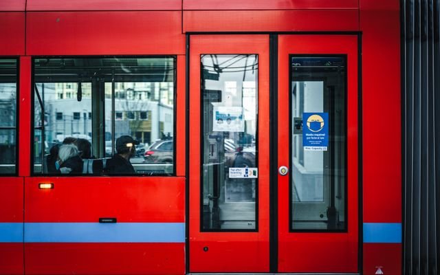 Side view of a red tram with commuters in an urban setting