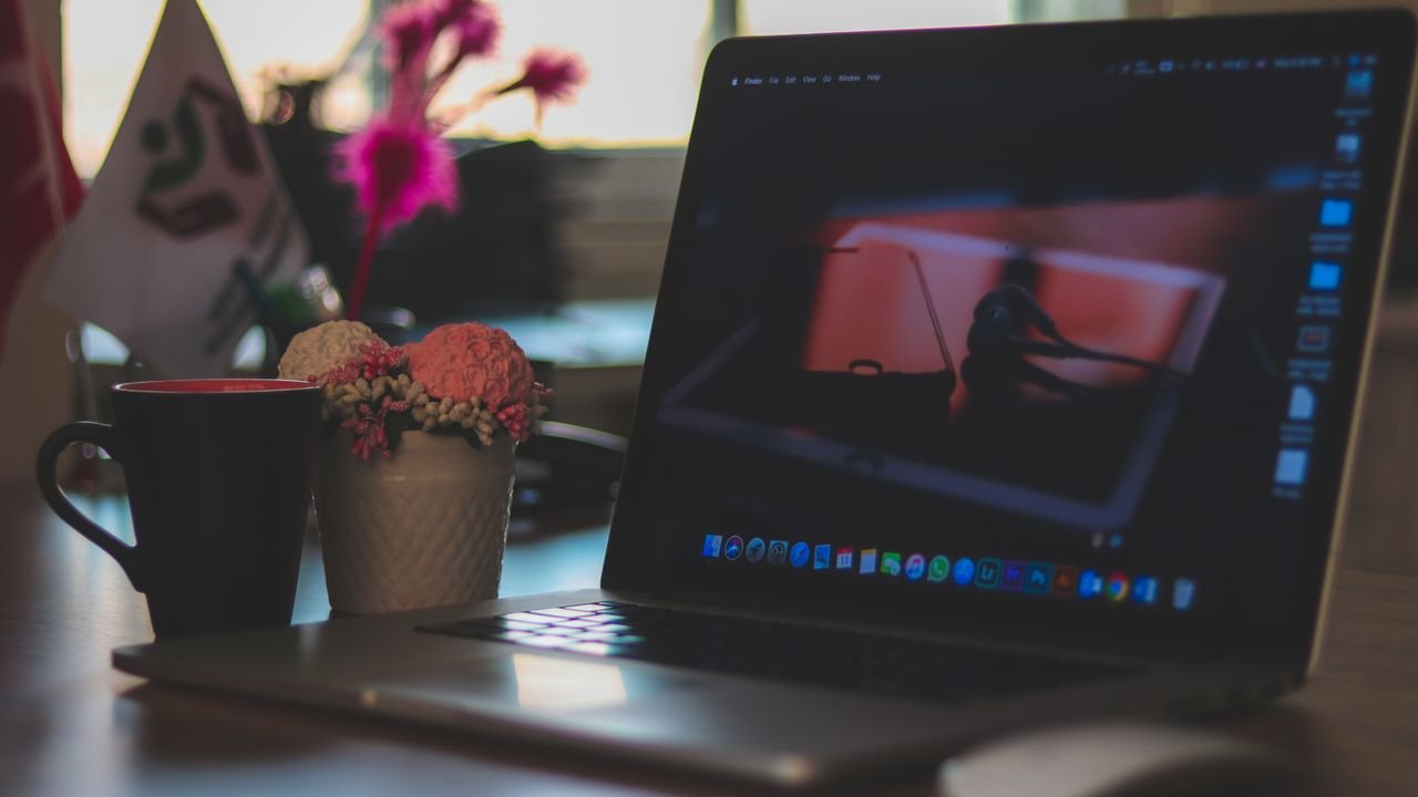 A modern workspace featuring a laptop, coffee cup, and decorative elements on a desk, ideal for remote work environments.