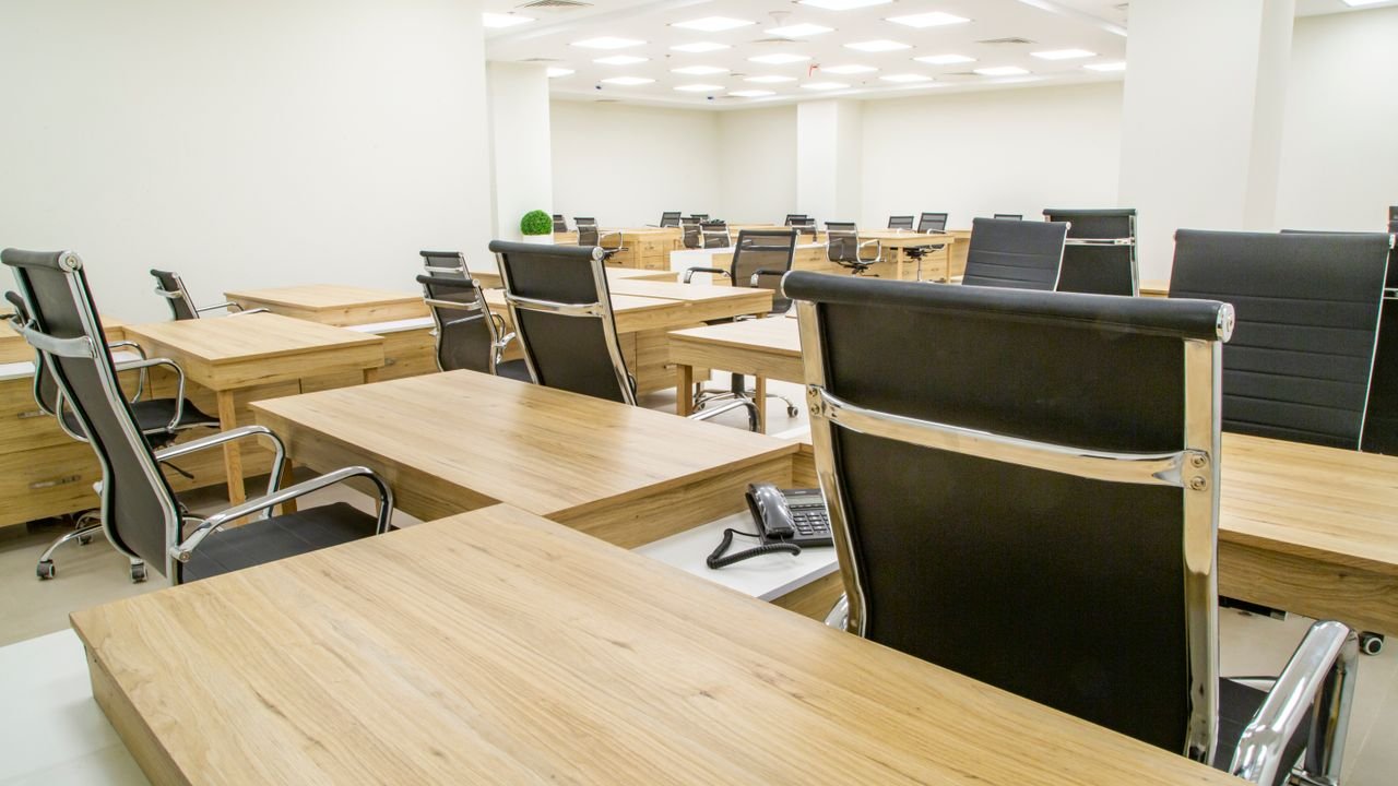 Spacious and modern empty office with wooden desks and ergonomic chairs.