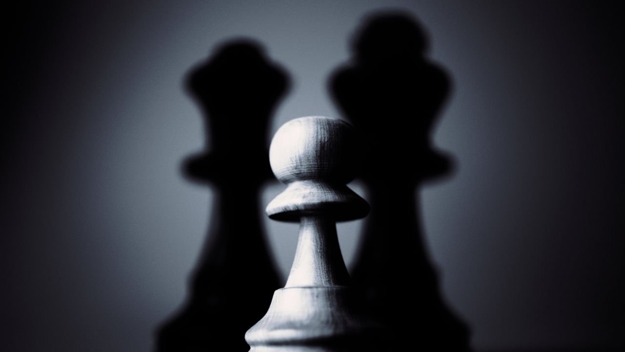 Moody black and white photograph of a chess pawn highlighting strategy and shadow play.