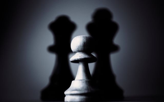 Moody black and white photograph of a chess pawn highlighting strategy and shadow play.