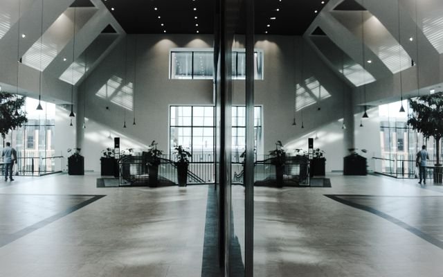 A modern, spacious indoor lobby featuring stunning architectural design and symmetrical reflections.