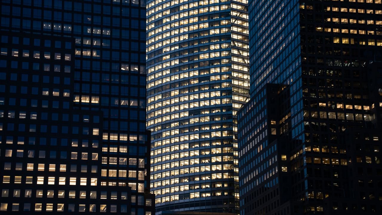 Skyscrapers with glowing windows create a vibrant nighttime cityscape.