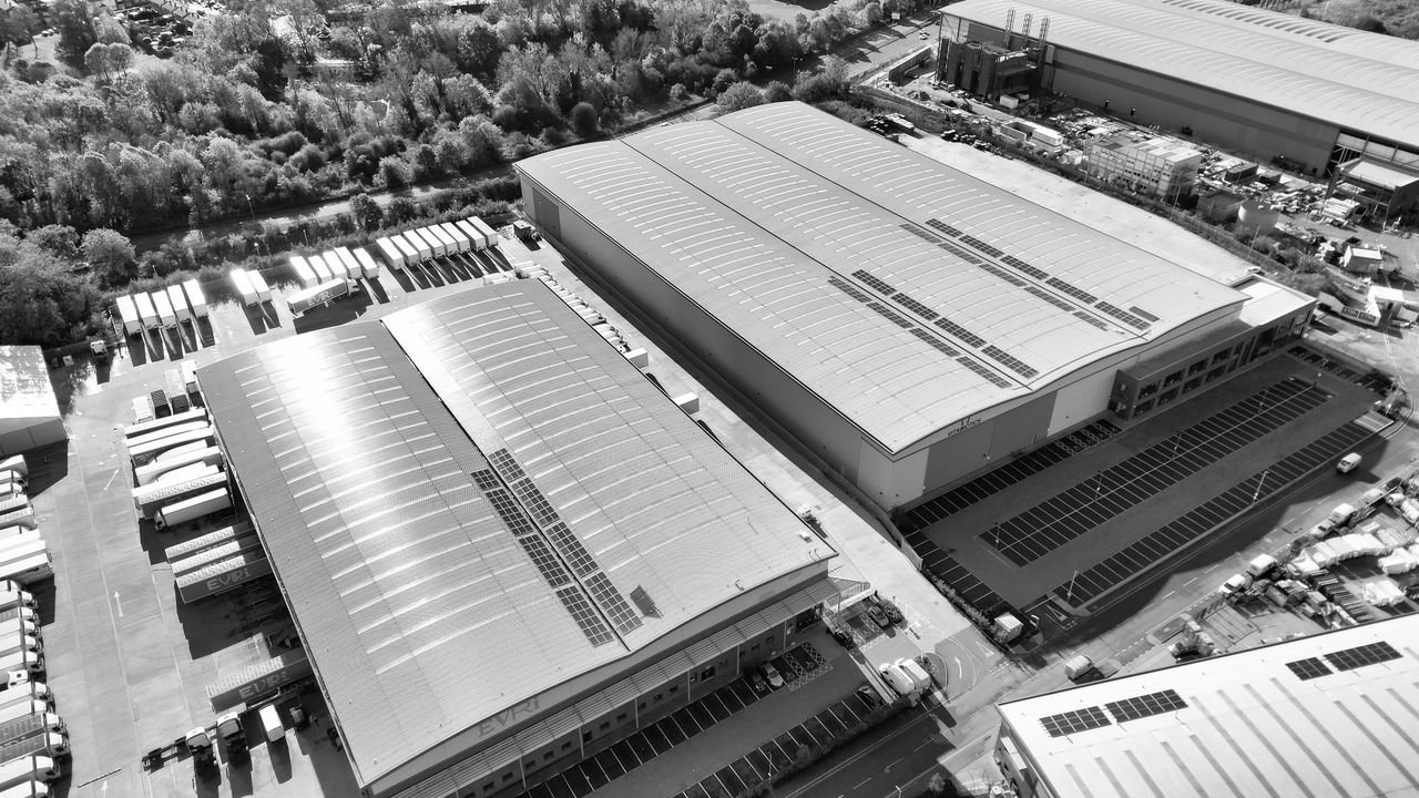 Aerial monochrome image of industrial warehouses and parking spaces in Hertfordshire, UK.