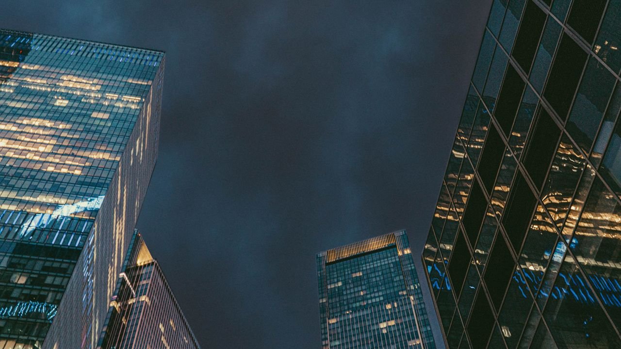 Low-angle shot of illuminated skyscrapers reflecting lights against a dark evening sky in Moscow.