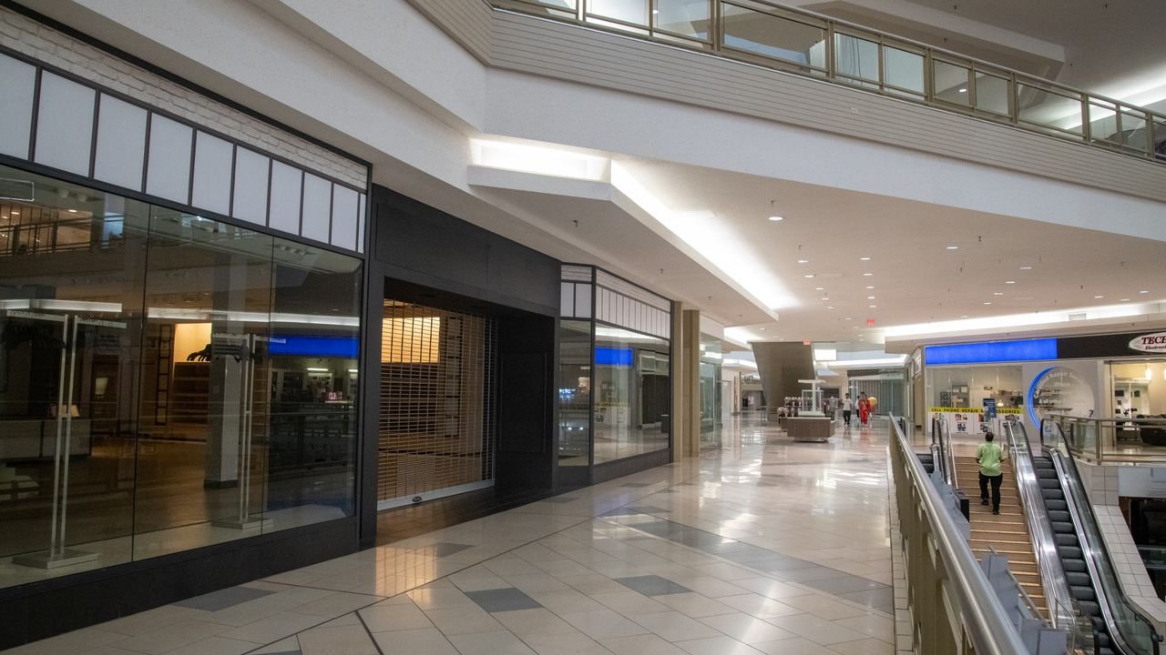Spacious and contemporary mall interior with closed stores and escalator.