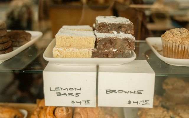 Delicious display of lemon bars and brownies in a bakery with price tags.