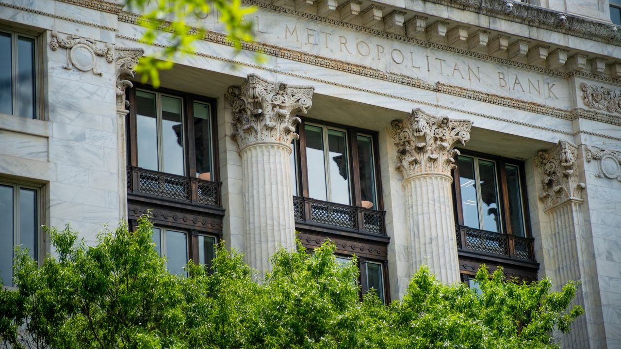 Close-up of the neoclassical columns and facade of Metropolitan Bank surrounded by greenery.