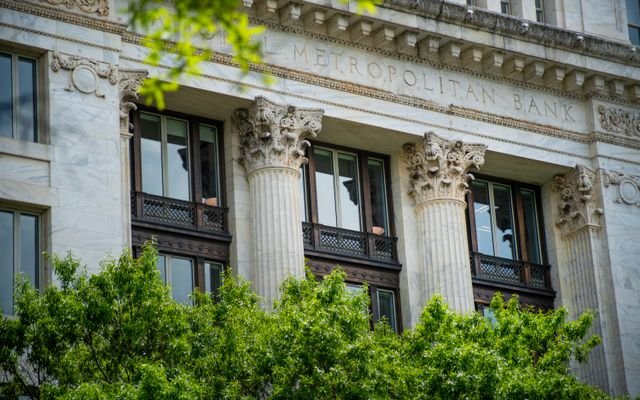 Close-up of the neoclassical columns and facade of Metropolitan Bank surrounded by greenery.