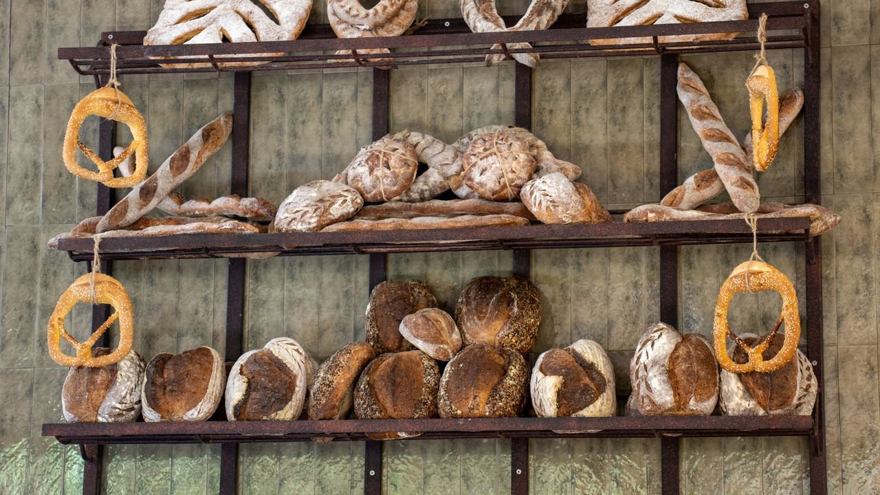 An assortment of artisan bread beautifully arranged on wooden shelves in a Bali bakery.