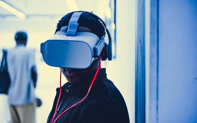 Young adult using a virtual reality headset with headphones in an indoor modern setting.
