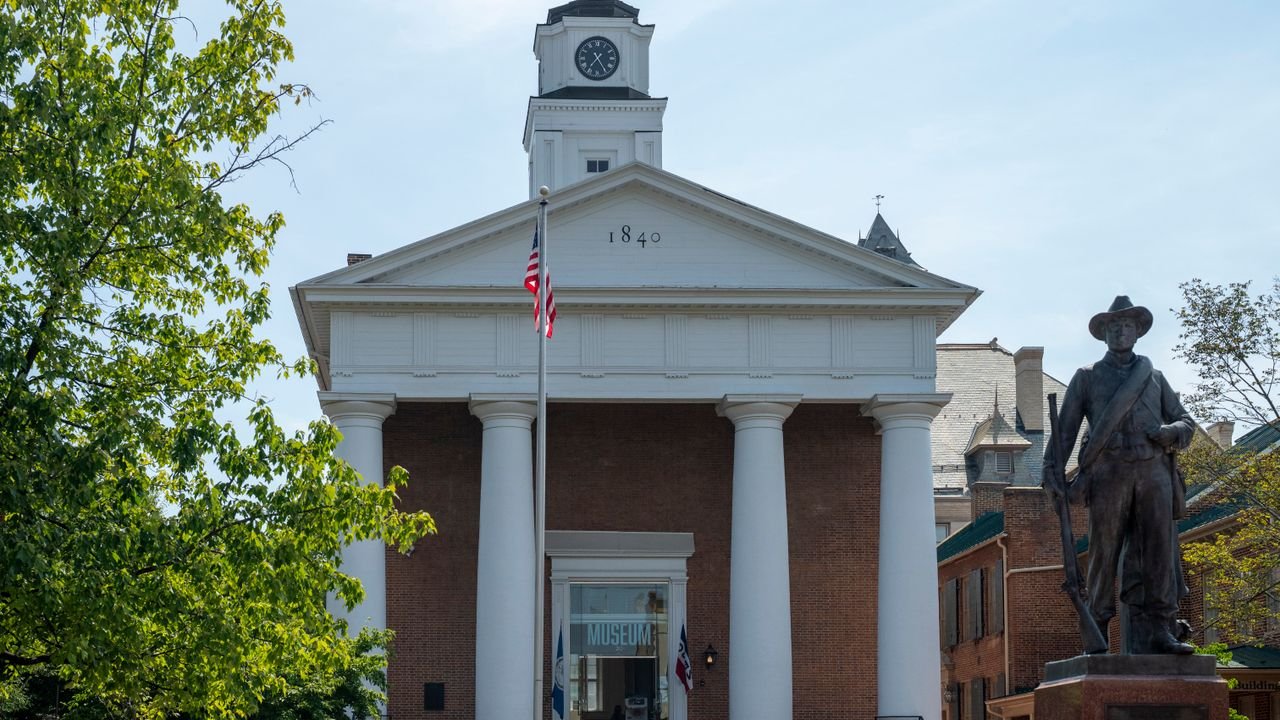 Historic courthouse facade with statue and American flag in daylight.