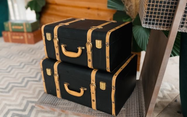 Stacked vintage black suitcases with tan straps create a nostalgic travel vibe.