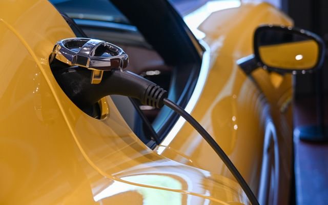 Close-up of a yellow electric vehicle charging with a plugged-in cable indoors.