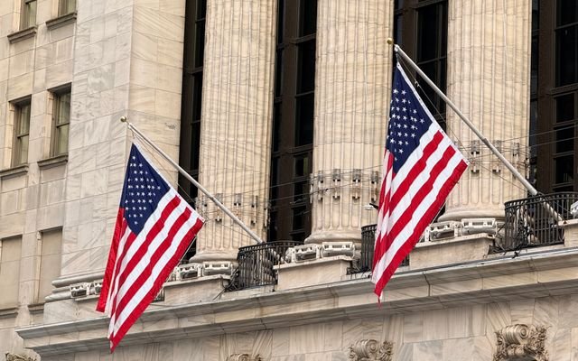 American flags displayed prominently on a historic Wall Street building in New York City.