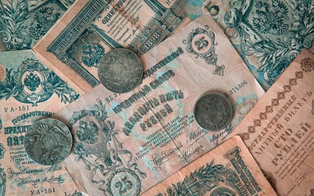 Collection of vintage Russian banknotes and coins featuring intricate designs.