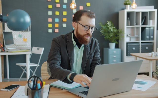 Business professional working diligently on laptop in a modern office space.