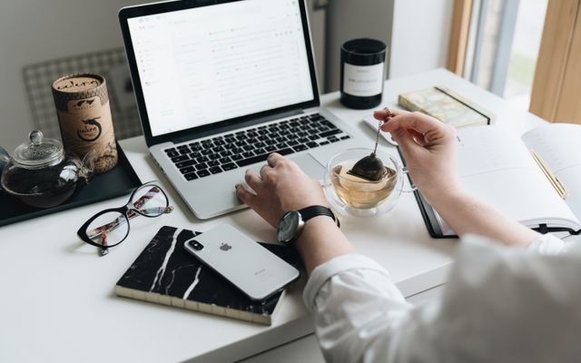 A cozy home office scene with a laptop, tea, and workspace essentials.