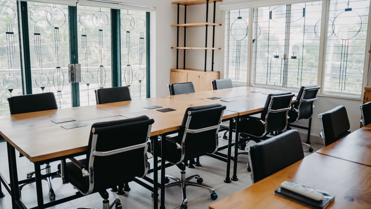 Spacious modern office conference room with black chairs and wooden tables.