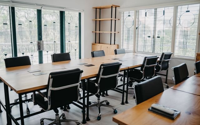 Spacious modern office conference room with black chairs and wooden tables.