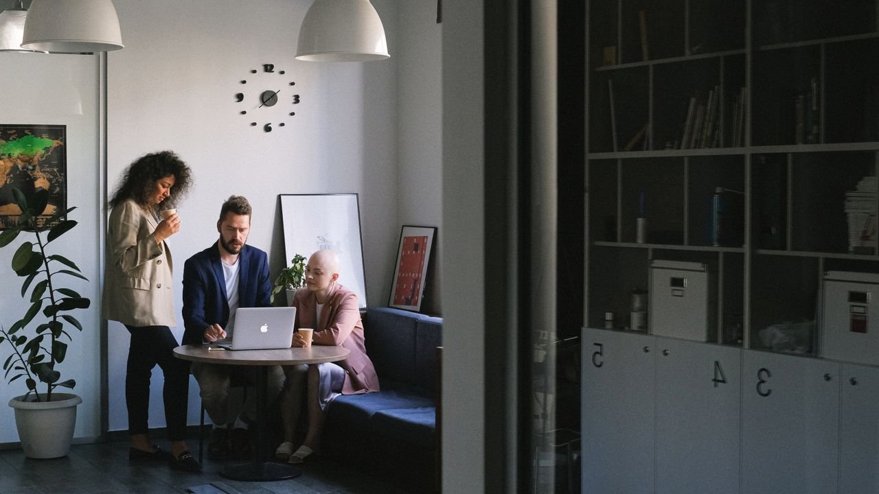 Multiethnic serious businesspeople working while browsing netbook at table in contemporary office with shelves