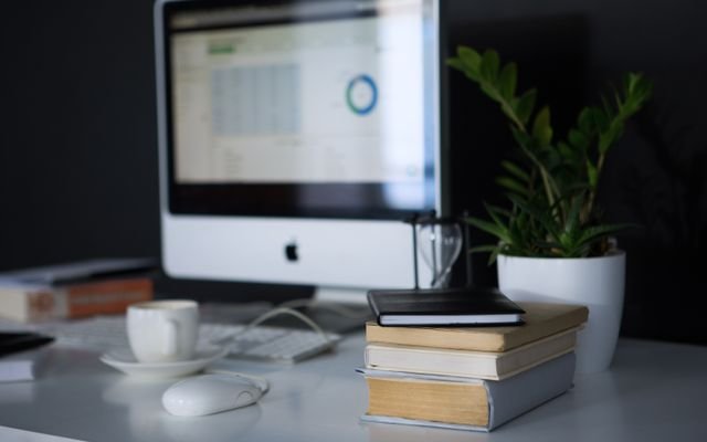 A sleek modern office setup featuring a computer, books, and a coffee cup on a desk.