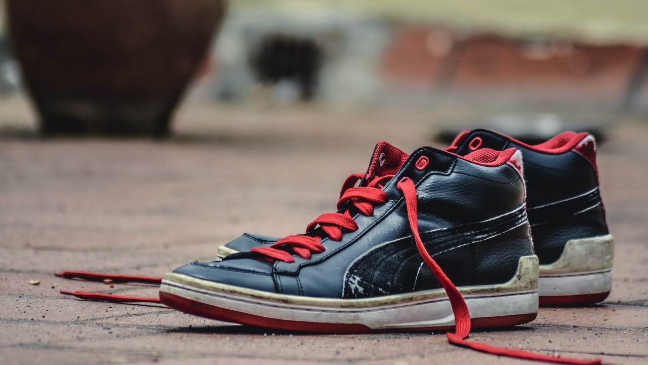 Close-up of rugged black and red sneakers on a brick pavement, showcasing urban style.