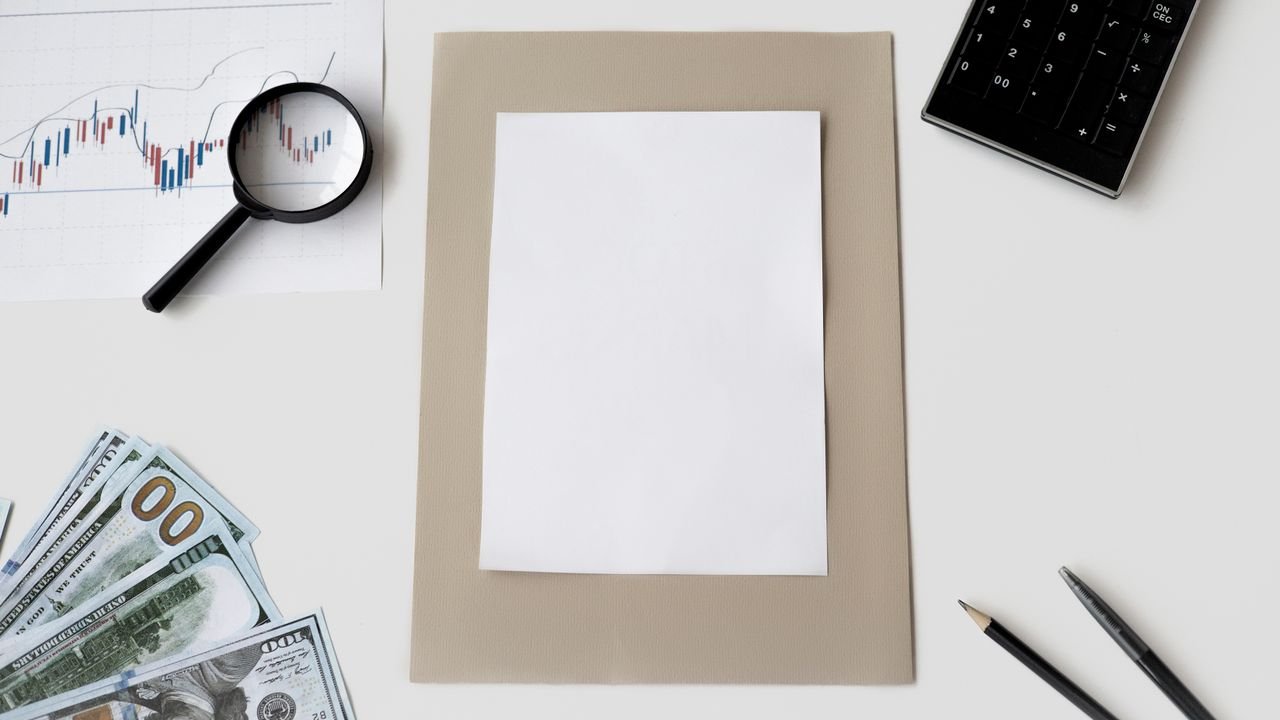 Flat lay of financial tools and blank paper for planning or mockup.