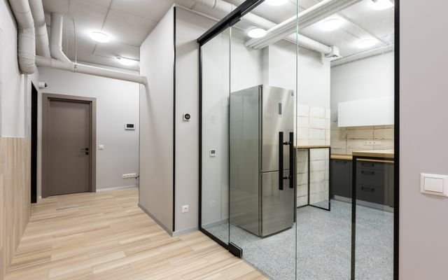Interior of spacious hallway and kitchen with counters and appliances in contemporary workplace
