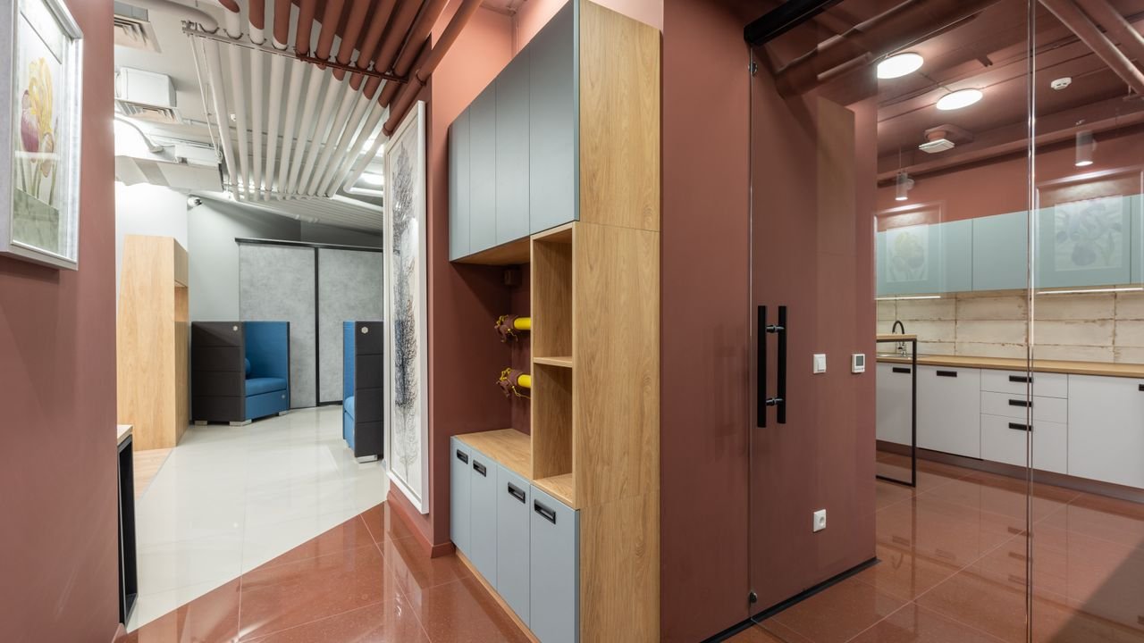 Corner of cabinet separating spacious workplace with new furniture and modern kitchen with counters and tiled floor