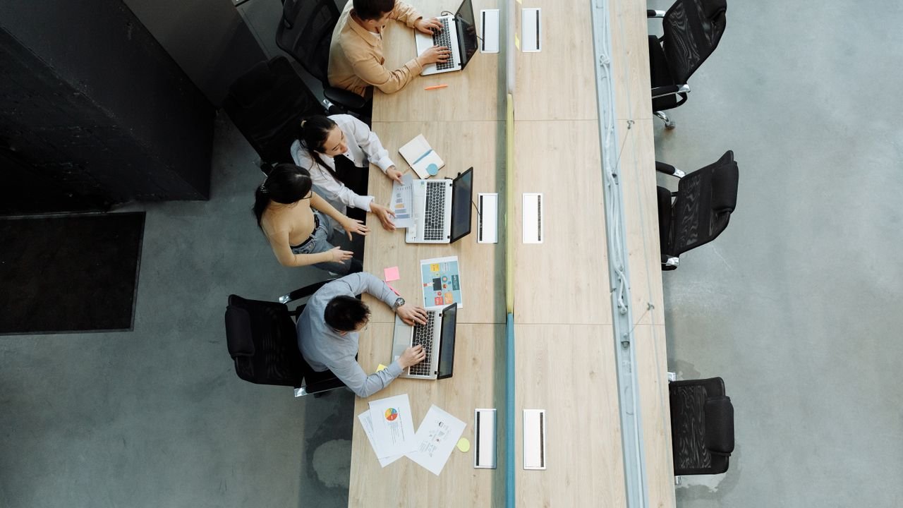 High angle view of colleagues working together on laptops in a modern office setting.