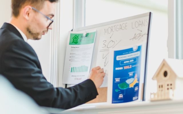 Real estate agent analyzing mortgage loan details on a whiteboard in an office setting.