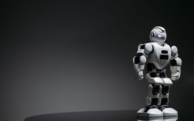 Compact humanoid robot toy standing on a reflective surface, exuding a futuristic vibe.