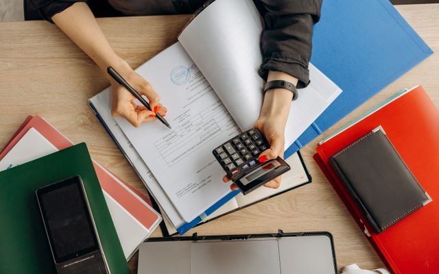 Accountant analyzing financial documents with a calculator on a desk, highlighting business tasks.