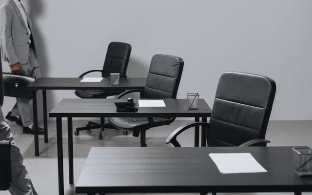 Contemporary office space with black leather chairs and desks, showcasing a minimalist design.