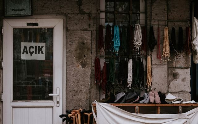 Outdoor display of colorful beads and accessories in front of an open door with Turkish sign.