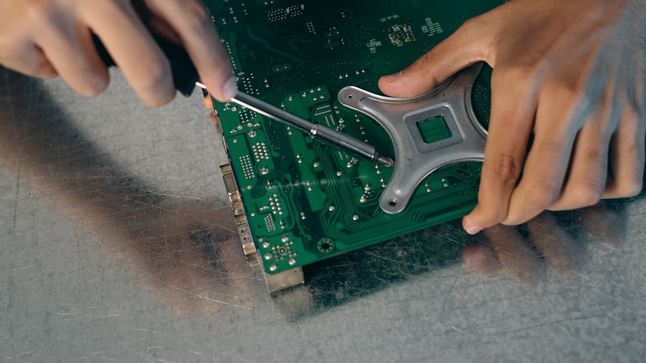 Detailed view of an engineer assembling a circuit board with a screwdriver.