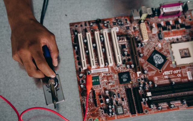 An engineer uses a soldering tool on a motherboard, showcasing technology and precision.