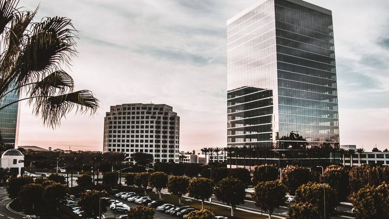 Vibrant cityscape with modern skyscrapers and palm trees during daytime.