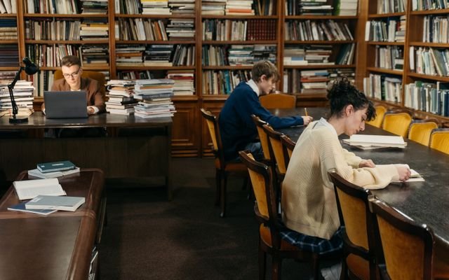 Students engaged in study inside a peaceful library with bookshelves.